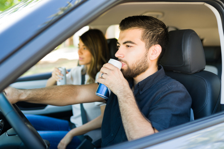 man drinking energy drink while driving